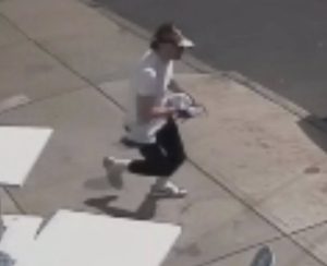 suspect with hat walking out of Giddy's restaurant with flag May 2026